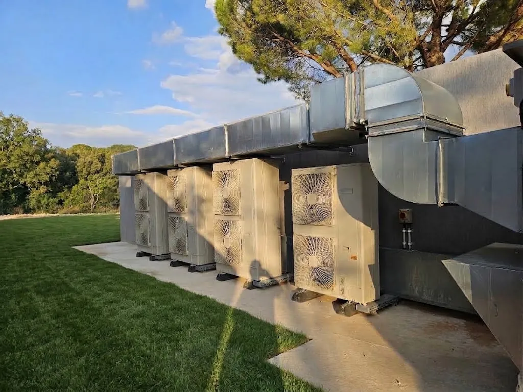 Unités extérieures de climatisation alignées le long d'une façade, avec gaines de ventilation